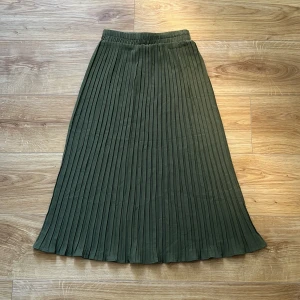 Grön ribbad kjol - Grön ribbad kjol från okänt märke (se bild). Det finns inga fler lappar på kjolen, men jag gissar på att den är gjord i polyester och att storleken är S. Aldrig använt. I bra skick!