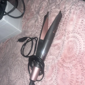 Remington vridbar plattång  - Bilden visar en plattång från Remington i metallic rosa och svart, köpt för 600.