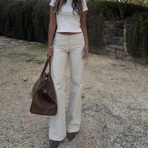 Beige wide byxor med låg midja - Avora ”forte” trousers. Snygga beige byxor med hög midja och wide fit. De har raka ben med lätt utsvängning och är tillverkade i ett mjukt bomullsmaterial. Storlek 34. 