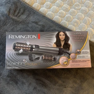 Hårborste - Rotating Air Styler från Remington med avancerad keramisk beläggning, infuserad med keratin och mandelolja. Setet innehåller flera borsthuvuden i svart och roséguld, samt en stylingmunstycke. Perfekt för att skapa volym och glansigt hår med 2-vägs rotation och 1000W effekt.