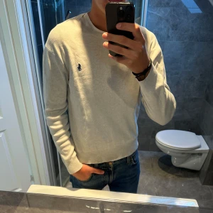Ljusgrå långärmad tröja från Ralph Lauren - En riktigt schysst grå tröja från Ralph lauren. Tröjan är i riktigt bra skick. Modellen på bilden är 188cm och strlk på tröjan är M. Tröjan är något liten på mig men beror på vad man föredrar för passform. Skicka iväg ett meddelande vid minsta lilla fundering;)
