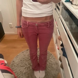 Rosa manchesterbyxor med stjärndetalj - Säljer ett par rosa manchesterbyxor från Lindex med snygga stjärnor broderade på bakfickorna. Byxorna har låg midja, raka ben och flätade detaljer vid linningen. Perfekt för dig som vill sticka ut med färg och coola detaljer.