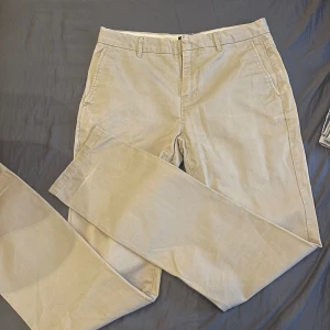 Beige chinos från Lyle & Scott - Snygga beige chinos från Lyle & Scott med klassisk passform och raka ben. 