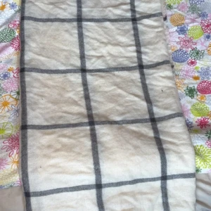 Beige rutig halsduk med fransar - Snygg beige halsduk med stora grå rutor och fransar i kanterna. Perfekt att svepa runt halsen för en chill och stilren look. Mjuk och skön, passar dig som gillar klassiska mönster och neutrala färger.