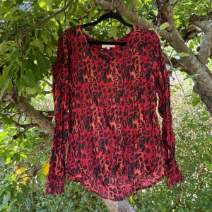 Röd leopardmönstrad blus från Cream - Säljer en röd blus från Cream i storlek 40 med leopardmönster i svart och orange. Blusen har v-ringad hals, långa ärmar med smock vid ärmslut och är gjord i ett lätt, flowy material som känns skönt mot huden. Perfekt för dig som gillar att sticka ut med färg och mönster. Mycket fint skick, jag hittar inga synliga anmärkningar eller defekter.