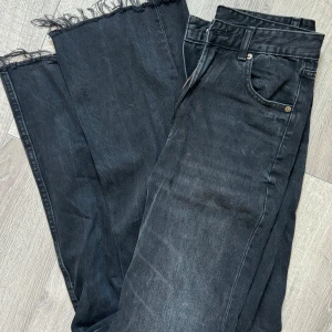 Svarta wide jeans från Zara - Säljer ett par svarta jeans från Zara med breda ben och råa, fransiga kanter längst ner. Klassisk femficksmodell med dragkedja och knapp framtill. Jeansen har en cool, mörk tvätt och är tillverkade i jeansmaterial.