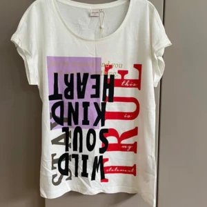 Vit t-shirt med tryck från Cream  - Vit t-shirt från Danska Cream med coolt grafiskt tryck i svart, rött och lila på framsidan. T-shirten har rund hals och korta ärmar, tillverkad i mjuk bomull. Perfekt för dig som gillar statement-plagg med attityd och färg.