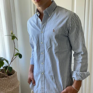Randig blå vit Ralph Lauren skjorta slim fit stretch Oxford skjorta  - Slim fit stretch Oxford Ralph Lauren skjorta, inga defekter! Modellen är 180,75 kg och bär L. 👌lite tjockare i materialet så perfekt för hösten nu! 🤞