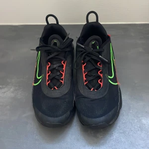 Nike Air Max 2090 svart/grön sneakers - Nike Air Max 2090 sneakers i svart med neongröna och röda detaljer. Snygg design med synlig Air Max-dämpning, mesh-ovandel och coola snörningar. Sulan är robust och har bra grepp. Perfekt för dig som gillar streetstyle och sportig vibe.