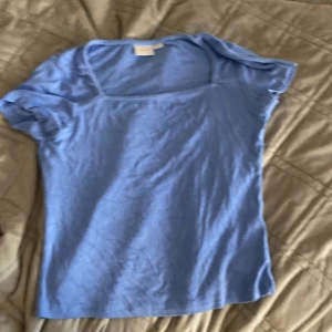 Ljusblå topp från Gina Tricot - Snygg ljusblå topp från Gina Tricot med korta ärmar och rundad hals. Enkel och stilren design i mjuk bomull som passar perfekt till jeans eller kjol. Perfekt för dig som gillar en clean och fräsch look.