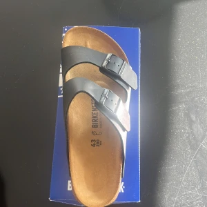 Birkenstock Arizona PROF svarta sandaler - Sprillans nya Birkenstock Arizona PROF sandaler i svart med två justerbara remmar och metallspännen. Fotbädden är tillverkad i naturkork och innersulan i skinn för extra komfort. Perfekt för chill dagar och enkel stil. Regular fit.