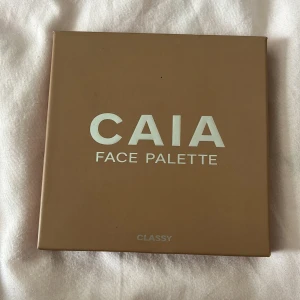 CAIA Face Palette Classy - Snygg ansiktspalett från CAIA i färgen Classy med fyra puderprodukter: contour i matt beige, bronzer i varm brun, blush i rosad ton och highlighter i skimrande guld. Paletten har en inbyggd spegel och stilren beige förpackning. Highlightern har används några gånger men har inte använt dom andra mycket alls kanske 2-3 gånger, skyddet på glaset är fortfarande på