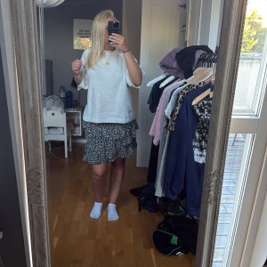 Blommig volangkjol från Stradivarius - Supersöt svart minikjol från Stradivarius med vita små blommor och volangdetaljer.