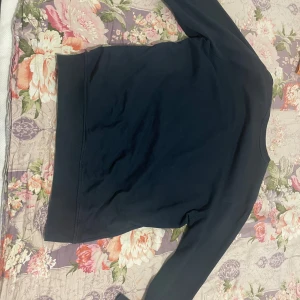 Mörkblå sweatshirt från Balmain - Snygg mörkblå sweatshirt från Balmain Paris med stort vitt tryck på bröstet. Tröjan har rund hals, långa ärmar och ribbade muddar vid ärmslut och nederkant. Perfekt för dig som gillar stilrena designer och vill ha ett statement-plagg i garderoben.