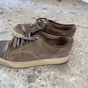 Bruna lanvins - Snygga sneakers från Lanvin i grå mocka med rund tå och platt sula. Skorna har klassisk snörning och en stilren design som passar till det mesta. Perfekta för dig som gillar en clean och avslappnad look. Passar även 43