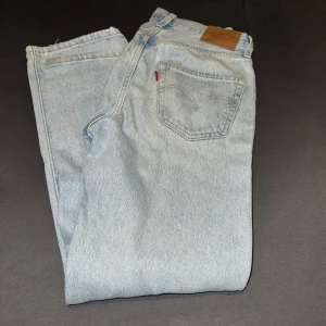 Levi's 501 ljusblå jeans - Säljer ett par klassiska Levi's 501 jeans i ljusblå tvätt. Modellen har rak passform, fem fickor och knappgylf. Jeansen är tillverkade i premium bomull och har den ikoniska läderpatchen bak i midjan. Perfekt för dig som gillar tidlös och chill stil.