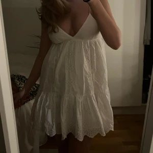Vit kort klänning  - Supersöt vit kort klänning med tunna axelband, coolt mönster och v-ringad hals 😍 Klänningen är från Zara men finns inte kvar på hemsidan 💕 Den är endast andvänd 1 skolavslutning och därför säljer ja den då den inte kommer till användning av mig 🥰 Skriv vid prisförslag eller frågor 😇