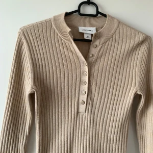 Beige ribbad långärmad tröja Monki - Säljer en beige ribbad långärmad tröja från Monki i storlek XS. Tröjan har en snygg knappslå med fem knappar framtill och en rundad hals. Materialet är mjukt och stretchigt.  Helt ny!