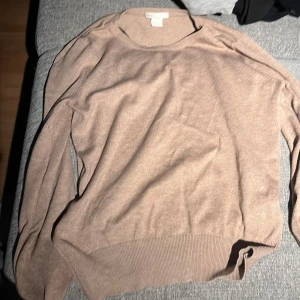 Beige stickad tröja från H&M BASIC - Säljer en enkel och snygg beige stickad tröja från H&M BASIC i storlek S. Tröjan har rund halsringning, långa ärmar och ribbade muddar vid nederkant och ärmslut. Perfekt för lager-på-lager och chill stil.