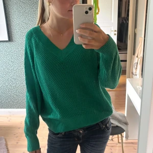 Grön stickad tröja med v-ringning Lindex - Snygg grön stickad tröja från Lindex i storlek L. Tröjan har en djup v-ringning, ribbade muddar och långärmad passform. Perfekt att slänga på sig när det är lite kyligt ute. Färgen är riktigt poppande och modellen är loose för en chill vibe.