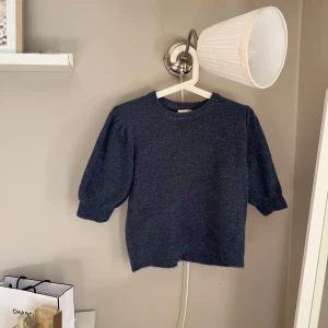 Mörkblå stickad tröja Gina Tricot - Mysig mörkblå stickad tröja från Gina Tricot i storlek 170. Tröjan har puffade trekvartsärmar och rund halsringning. Perfekt för dig som gillar enkel men snygg stil med lite volym på ärmarna. Passar till jeans eller kjol för en chill look. Endast använd 2 ggr