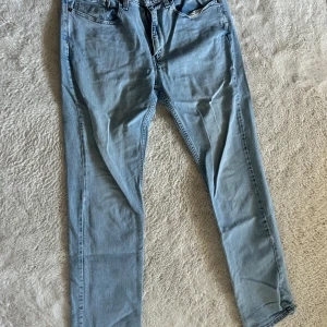 Levis 504 ljusblå jeans - Ljusblå Levis 504 jeans med klassisk femficksdesign och raka ben. Jeansen har en snygg vintage-vibe med tydlig Levis-patch bak i midjan och diskreta sömmar på bakfickorna. Perfekt för dig som gillar en chill och tidlös stil.