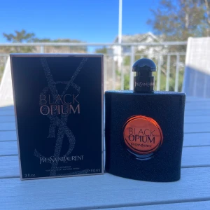 Yves Saint Laurent Black Opium EdP 90ml - Black Opium Eau de Parfum från Yves Saint Laurent, 90ml. Flaskan är svart med glittrig finish och har en rund, orange detalj i mitten med loggan. Lock och spraymunstycke i svart plast. Snygg och modern design som sticker ut på hyllan.