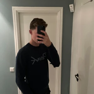 Blå stickad Peak Performance tröja - Snygg mörkblå stickad tröja från Peak Performance med stort Peak-tryck över bröstet. Rund hals och ribbade muddar vid ärmslut och nederkant. Perfekt för dig som gillar stilren design och vill ha en tröja som funkar till jeans eller chinos.