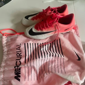 Nike Mercurial Xi motion blur elite pris kan diskuteras  - Säljer ett par Nike Mercurial fotbollsskor i en snygg rosa och vit färg med svarta detaljer. Skorna har snörning, låg profil och en rund tå. Yttermaterialet är syntet och designen har ribbade linjer för extra grepp. Perfekt för dig som vill sticka ut på planen!