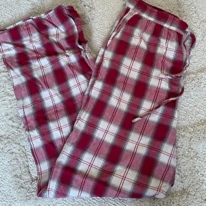 Röd- och vitrutiga mjukisbyxor - Säljer ett par röd- och vitrutiga pyjamasbyxor med snörning i midjan.  Byxorna har en loose passform. Passar bra på de som är 170 och kortare