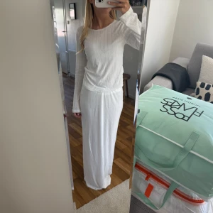 Pointelle set - Säljer ett vit set i pointelle med långärmad topp och rak kjol med slits. Settet har en clean och enkel look med rund halsringning och mjukt, stretchigt material som sitter skönt mot kroppen. Perfekt för dig som gillar minimalistisk stil.
