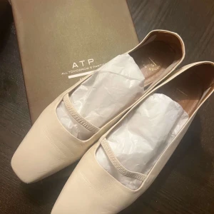 Beige ballerinaskor från ATP Atelier - Stilrena ballerinaskor från ATP Atelier i beige skinn med fyrkantig tå och tunn elastisk rem över foten. Skorna har platt sula och är handgjorda i Italien. Perfekta för dig som gillar minimalistisk och modern design. Köpta för 3500kr