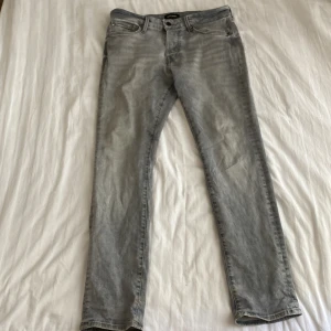 Grå slim jeans från Jack & Jones - Snygga ljusgrå jeans från Jack & Jones i modellen Slim Glenn. Jeansen har klassisk femficksdesign, smal passform och är tillverkade i mjukt denimtyg. Perfekta för dig som gillar en stilren och modern look.