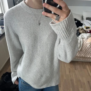 Ljusgrå tjock tröja - Mysig ljusgrå tröja med långa ärmar och ribbade muddar. Perfekt för kyliga dagar och ger en avslappnad look. Passar bra till jeans eller leggings.