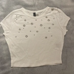 Vit croppad topp med metalldetaljer H&M - Säljer en vit croppad topp från H&M med coola silvriga metalldetaljer framtill. Tyckte denna var cool när jag köpte den men har faktiskt inte använt den en enda gång, därför säljs den❤️