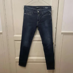 Mörkblå Replay  jeans - Snygga mörkblå jeans från Replay med klassisk femficksdesign och diskreta slitningar. Jeansen har smal passform och är tillverkade i stretchigt jeansmaterial för en bekväm känsla. Perfekta för dig som gillar en stilren och modern look.