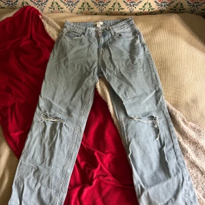 Ljusblå ripped jeans från H&M - Säljer ett par ljusblå jeans från H&M i storlek 38. Jeansen har raka ben och slitna detaljer vid knäna för en cool, avslappnad look. Klassisk femficksmodell med knapp och dragkedja. 