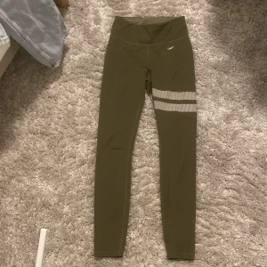 Tränings leggings - Snygga olivgröna leggings från Stronger, lite slitage på ”stronger märket” som man kan se på bilden. Annars är byxorna i bra skick