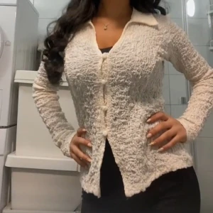 Beige crinkle skjorta med knappar - Säljer en beige långärmad skjorta från Gina Tricot med crinkle-effekt och stora tygklädda knappar framtill. Skjortan har klassisk krage, figurnära passform och är tillverkad i ett lätt, strukturerat material. 