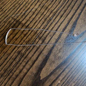 Minimalistiskt guldhalsband - Snyggt och stilrent halsband i guld med en tunn kedja och en böjd stav som hänger horisontellt. Perfekt för dig som gillar enkel och modern design. Passar till alla outfits och är lätt att matcha med andra smycken.