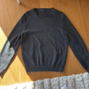Mörkgrå stickad tröja Polo Ralph Lauren - Mörkgrå stickad tröja från Polo Ralph Lauren. Den är riktigt skön. Om ni undrar något hör av er alla frågor är intressanta 