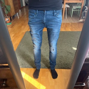 Blå skinny jeans Jack & Jones - Säljer ett par blå skinny fit jeans från Jack & Jones, modell Liam. Jeansen har klassisk femficksdesign, smal passform och är tillverkade i stretchig denim för extra komfort. Snygg tvättad look med lätt slitning på knä och lår.