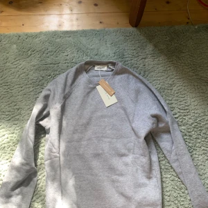 Grå sweatshirt från Pier One - Snygg grå sweatshirt från Pier One i storlek S. Tröjan har en klassisk rund halsringning och långa ärmar. Tillverkad i mjuk bomullsmix som är skön mot huden. Perfekt för chill dagar och enkel att matcha med jeans eller joggers. Sälj pågrund utan fel strl. Obs skriv innan köp
