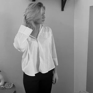 Vit oversized skjorta med ficka - Vit oversized skjorta från H&M i bomull med klassisk krage, bröstficka och knappar framtill. Skjortan har långa ärmar och en avslappnad passform som ger en chill vibe. Perfekt att styla med jeans eller kjol för en clean look.🤍