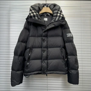 Svart Burberry Puffer Jacka/Väst - Snygg svart dunjacka från Burberry med quiltad design och dragkedja. Jackan har en avtagbar huva med ett klassiskt rutigt mönster i grått och vitt. Perfekt för kyliga dagar. Det är storlek M men är lite liten i storlek. Kan också göras om enkelt till en väst.