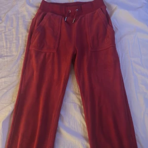 Röda Juicy Couture XXS - Röda mjukisbyxor från Juicy Couture i storlek XXS. Byxorna har bred resår i midjan med snörning, två stora fickor fram och broderad JC-logga på ena fickan. Mjukt material och klassisk straight fit som ger en chill vibe.