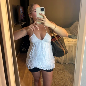 Vintage topp med volanger  - Supersöt vit linnetopp med smala halterneckband och v-ringad byst. Toppen är ärmlös och har en lätt rynkad struktur i tyget samt öppen rygg. Perfekt för varma dagar och ger en chill sommarkänsla. Den ser väldigt skrynklig ut på bilderna då jag inte använt den på ett tag, men det är bara att stryka 🥰