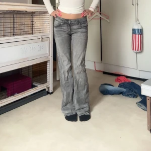 Grå bootcut jeans med låg midja - Säljer ett par grå jeans med snygg bootcut och låg midja. Jeansen har klassiska fickor fram och bak med coola detaljer på bakfickorna. Perfekta för dig som gillar en avslappnad men trendig look.