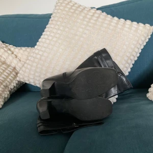 Svarta stövlar med klack och spänne - Säljer ett par svarta stövlar i skinn med snygga detaljer som dubbla spännen och dragkedja på insidan. Stövlarna har rund tå och hög klack, samt rynkade partier på skaftet för en cool look. Perfekta till höst och vinter!