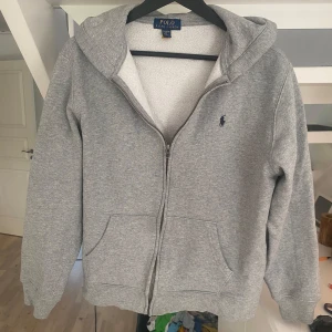 Grå hoodie från Polo Ralph Lauren  - Snygg grå hoodie från Polo Ralph Lauren i storlek XL barn som motsvarar XS/S i vuxen storlek. Väldigt najs och chill tröja som alltid är ett bra val av klädesplagg. Ny pris 1600 mitt pris 399